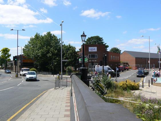 View of main road with modern buildings to the right, on a sunny day