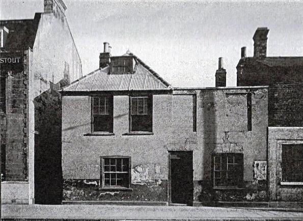 view showing a rather dilapidated two storey double-fronted building, two windows on upper floor bricked up