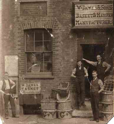 View outside basket makers' premises: man and three sons with a range of baskets on display