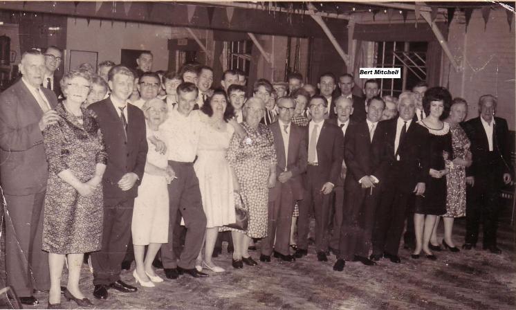 Inside photo, around 40 people, men in suits, ladies in dresses, some bunting, dark outside but no Christmas decorations visible