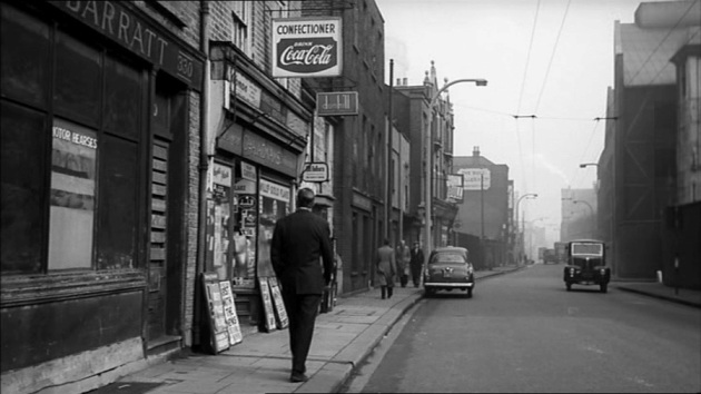 Man in suit walking along High Street away from camera