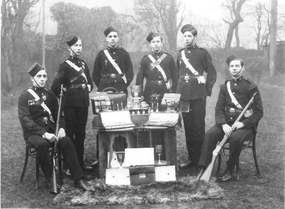 Six youths posed outside around a table of trophies